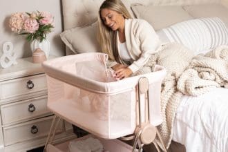Baby bedside sleeper bassinet in pink with height adjustment and storage basket