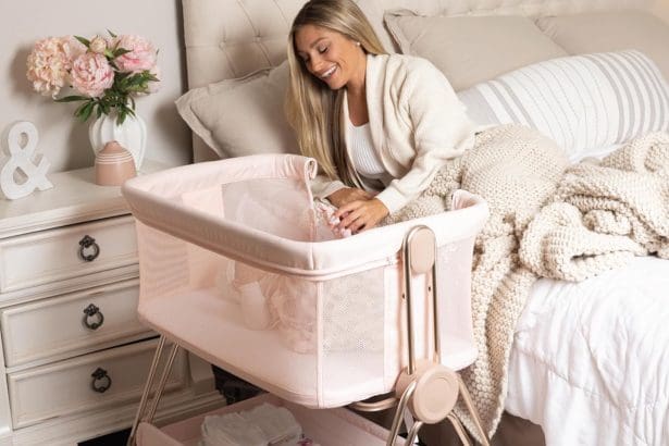 Baby bedside sleeper bassinet in pink with height adjustment and storage basket