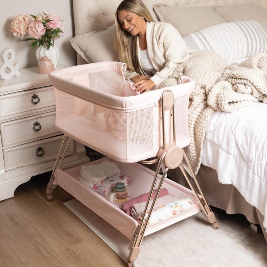 Baby bedside sleeper bassinet in pink with height adjustment and storage basket